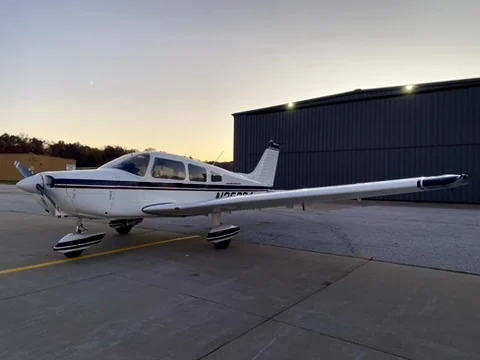 Piper Warrior N32204 parked near a hangar at dusk