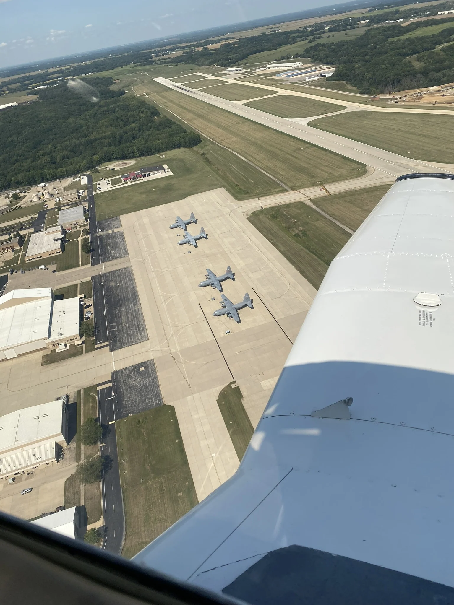 Aerial view of the airport ramp and several parked military transport aircraft from a general aviation airplane