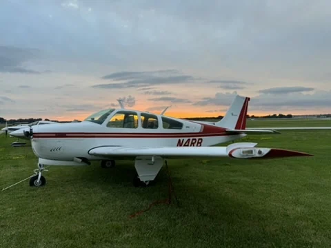 Beechcraft Bonanza N4RB parked on grass beneath an evening sky
