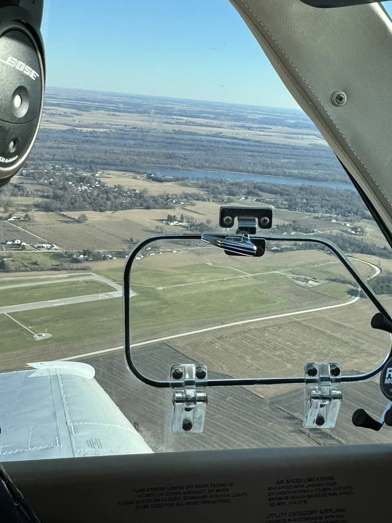 Side-window view over terrain and a runway from an airplane in flight