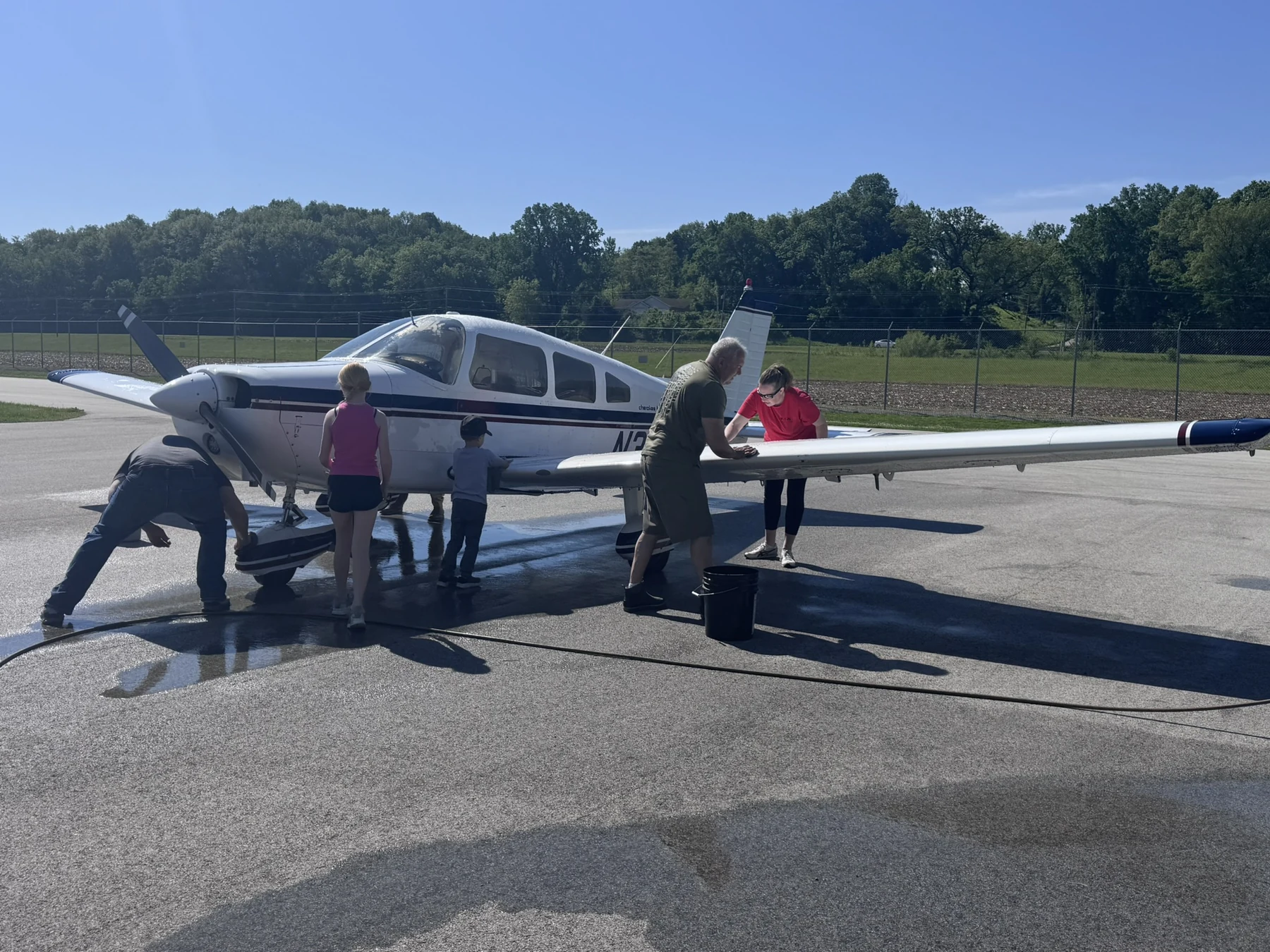 Flying Country Club volunteers of different ages washing the Piper Warrior together on the ramp